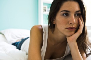 Woman lying on bed looking away contemplatively